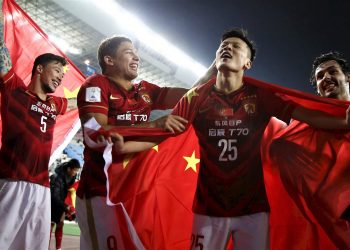 Zou Zheng (25) of China's Guangzhou Evergrande holds Chinese national flag as he celebrates with teammates after winning their Club World Cup quarter-final soccer match against Mexico's Club America during in Osaka, western Japan, December 13, 2015.  Asian champions Guangzhou Evergrande scored twice in the last 10 minutes, including a stoppage time winner from midfielder Paulinho, in a stunning 2-1 win over America in the Club World Cup on Sunday. REUTERS/Thomas Peter - RTX1YG73
