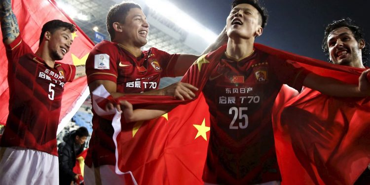 Zou Zheng (25) of China's Guangzhou Evergrande holds Chinese national flag as he celebrates with teammates after winning their Club World Cup quarter-final soccer match against Mexico's Club America during in Osaka, western Japan, December 13, 2015.  Asian champions Guangzhou Evergrande scored twice in the last 10 minutes, including a stoppage time winner from midfielder Paulinho, in a stunning 2-1 win over America in the Club World Cup on Sunday. REUTERS/Thomas Peter - RTX1YG73