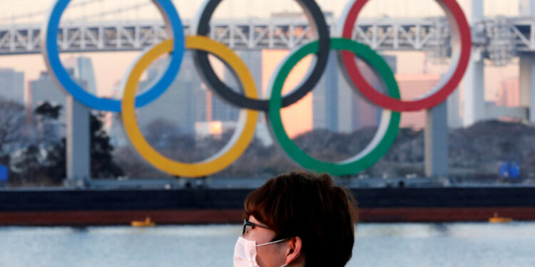 FILE PHOTO: A man wears a protective mask amid the coronavirus (COVID-19) outbreak in front of the giant Olympic rings in Tokyo, Japan, January 13, 2021. REUTERS/Kim Kyung-Hoon//File Photo