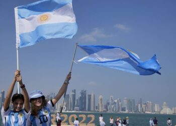 Two Argentina's soccer fans hold their country's flag on the eve of the World Cup group C soccer match between Argentina and Saudi Arabia, in Doha, Monday, Nov. 21, 2022. (AP Photo/Jorge Saenz)