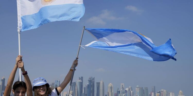 Two Argentina's soccer fans hold their country's flag on the eve of the World Cup group C soccer match between Argentina and Saudi Arabia, in Doha, Monday, Nov. 21, 2022. (AP Photo/Jorge Saenz)