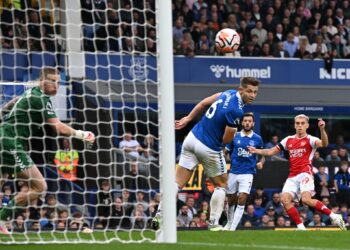Arsenal's Belgian midfielder #19 Leandro Trossard (R) watches as his shot beats Everton's English goalkeeper #01 Jordan Pickford (L) for the opening goal of the English Premier League football match between Everton and Arsenal at Goodison Park in Liverpool, north west England on September 17, 2023. (Photo by Paul ELLIS / AFP) / RESTRICTED TO EDITORIAL USE. No use with unauthorized audio, video, data, fixture lists, club/league logos or 'live' services. Online in-match use limited to 120 images. An additiona