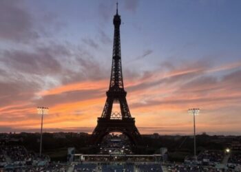 Spectators photograph a colorful sunset at Eiffel Tower Stadium prior to a beach volleyball match between The United States and Canada at the 2024 Summer Olympics, Saturday, July 27, 2024, in Paris, France. (Wally Skalij/Los Angeles Times)